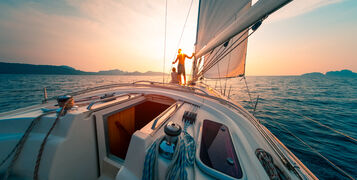 Young,Couple,Enjoys,Sailing,In,The,Tropical,Sea,At,Sunset