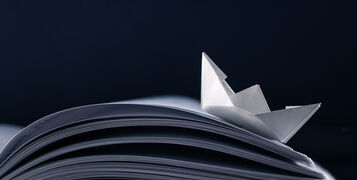 Paper,Boat,Floating,On,The,Pages,Of,A,Notebook.